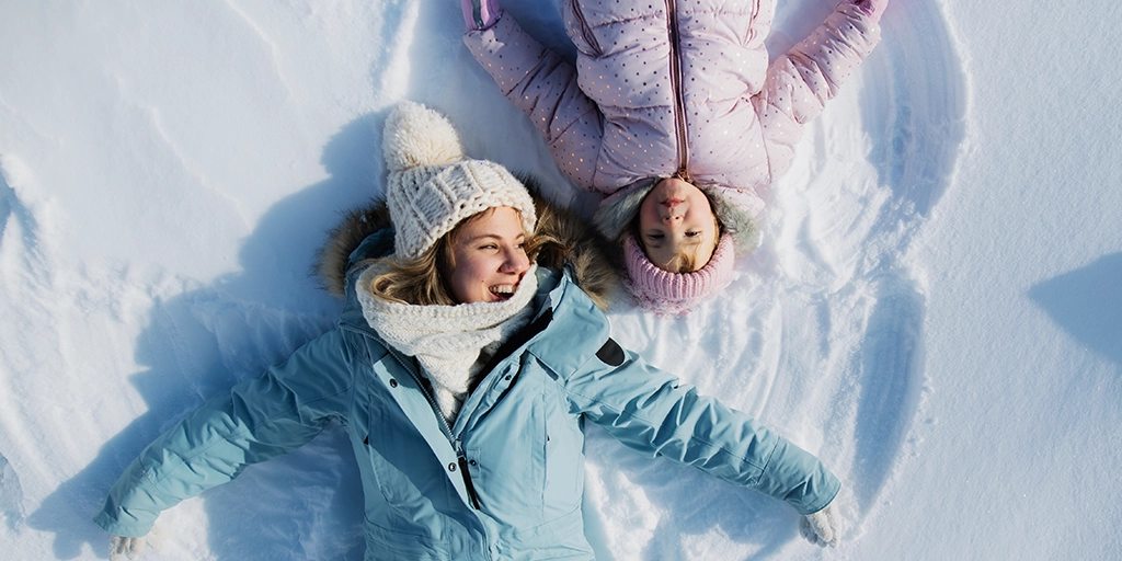 A mother and her daughter enjoying winter sensory activities for autistic kids outdoors.