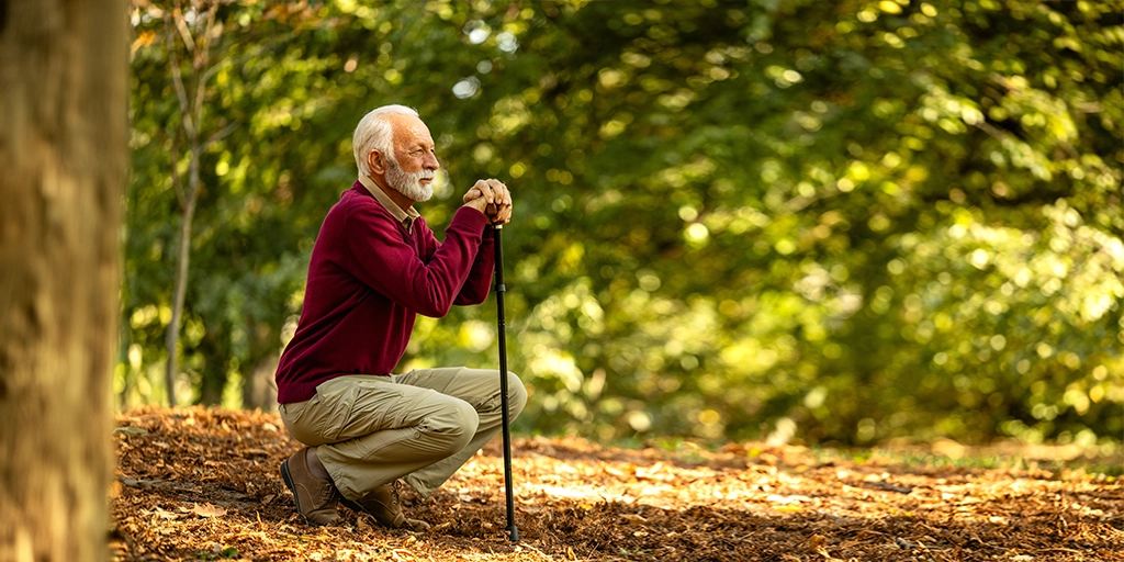An elderly man in a serene park setting, representing the importance of safe outdoor environments for dementia patients to reduce the risk of wandering.