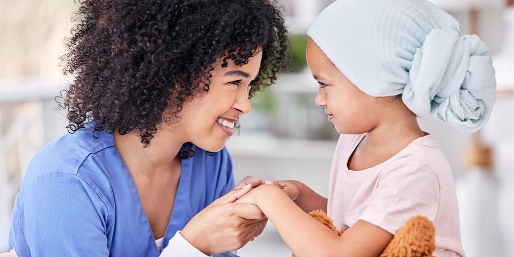 A nurse shares a joyful moment with a young child wearing a head wrap